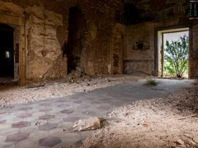 In cima alla rampa ammiriamo un ampio salone, nel quale si calpesta di nuovo un pavimento a mattonelle esagonali, stavolta grigie e rosse